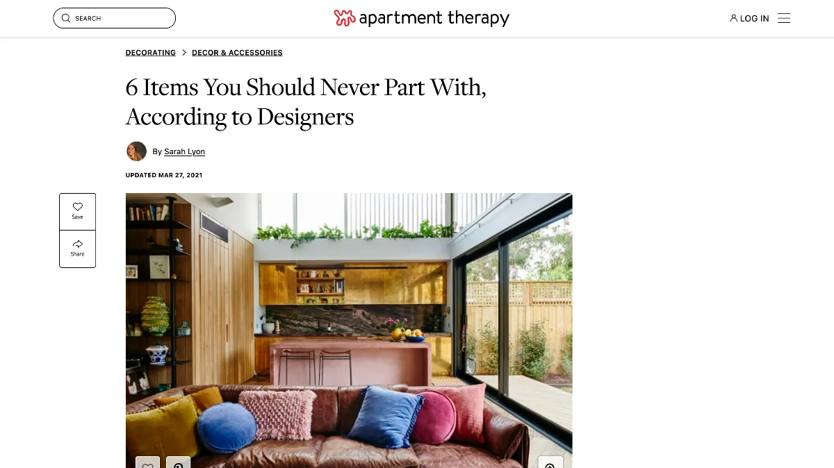 A screenshot of a website article showing a warm, open-concept room features a brown leather sofa with bright pillows. The modern kitchen has metallic gold cabinets and a pink central bench counter.