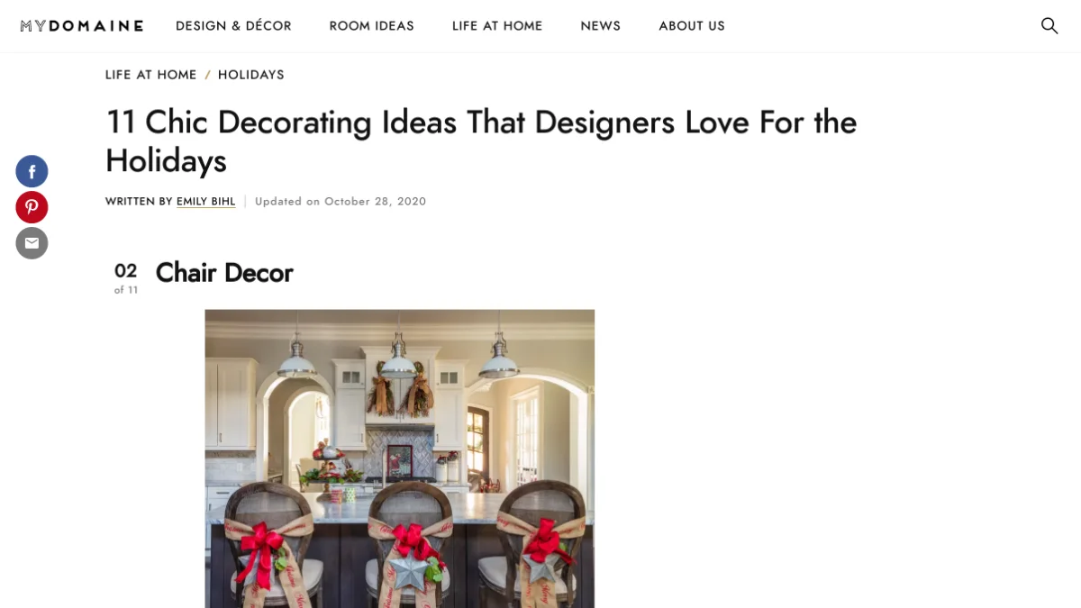 A screenshot of the MYDOMAINE article showing a holiday kitchen scene showing three dark wooden bar chairs adorned with burlap ribbons, bright red bows, and silver star ornaments.