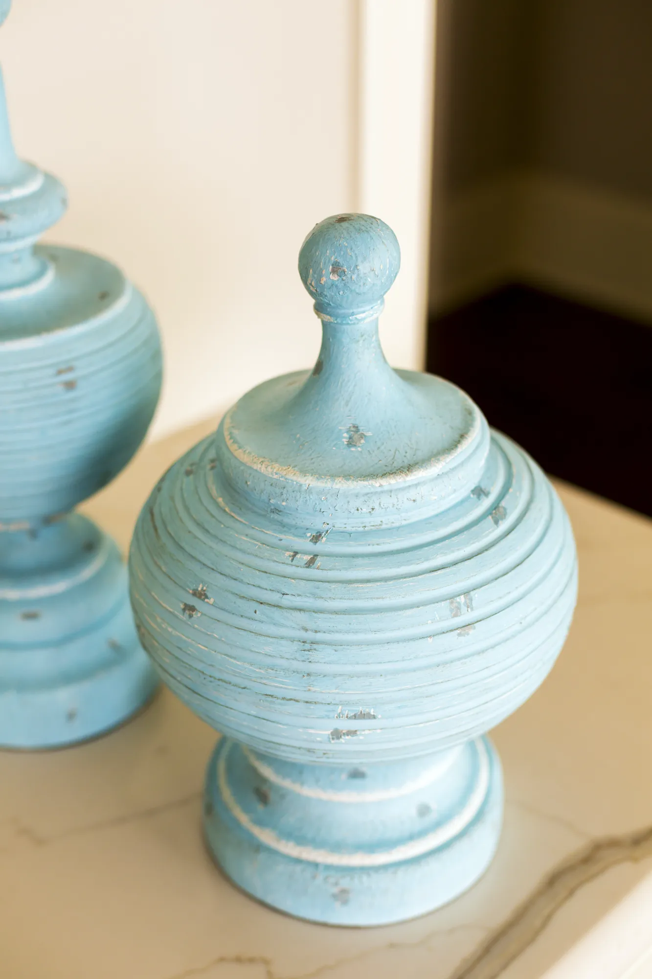 A close-up of a blue wooden decorative object with a distressed paint finish and concentric rings, displayed on a marble surface.