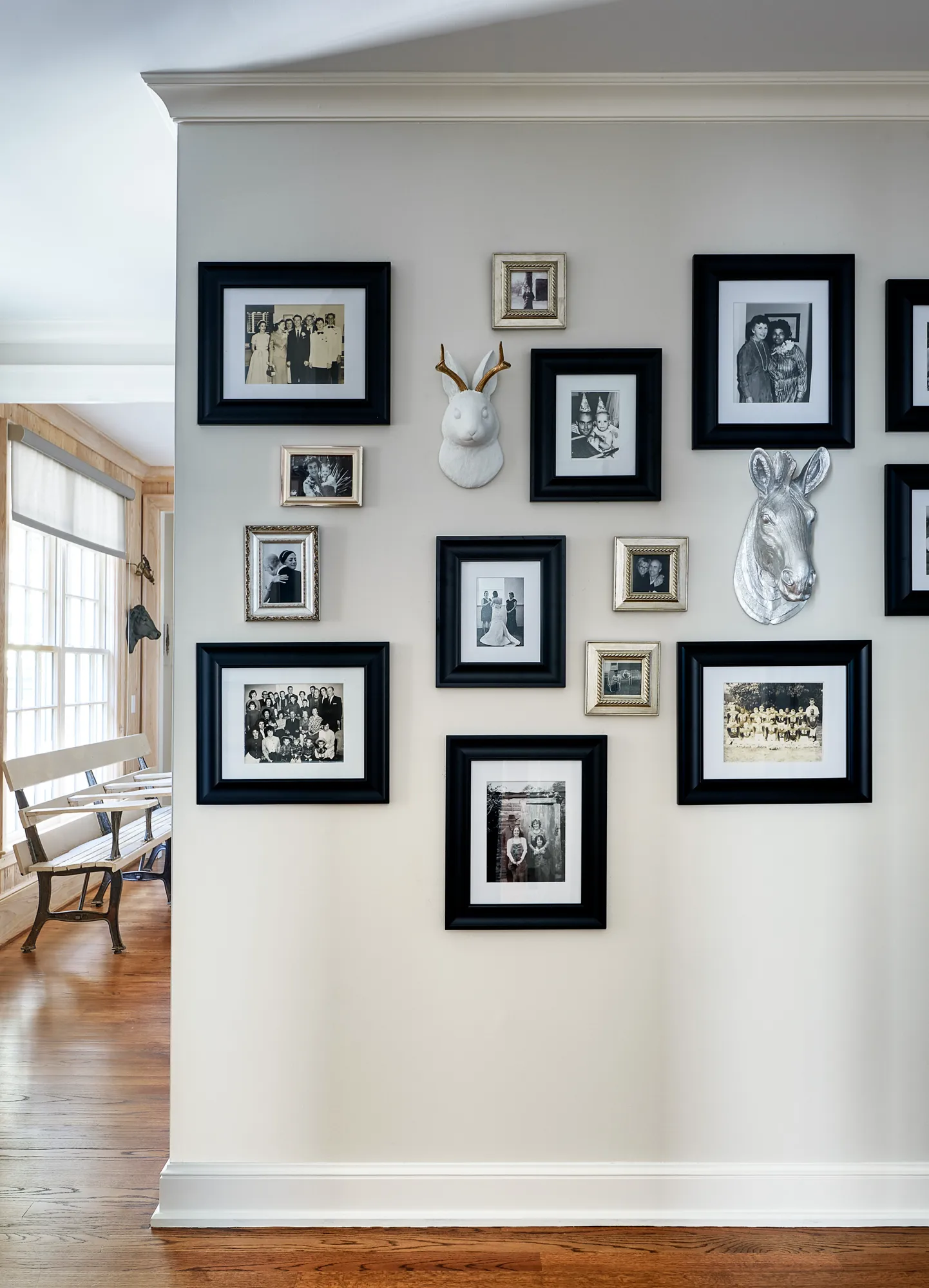 A gallery wall displays an assortment of framed black and white family photos, flanking decorative rabbit and horse head sculptures.